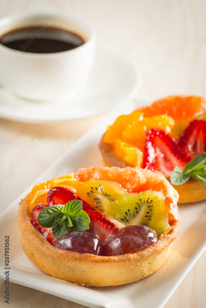 Photo of a fruit and berry tart dessert with toss sugar on wooden background. Fresh delicious sweet cake with raspberries, grapes, strawberries, cherry, kiwi, grapefruit and cream. Photo of a fruit and berry tart dessert with toss sugar on wooden background. Fresh delicious sweet cake with raspberries, grapes, strawberries, cherry, kiwi, grapefruit and cream.