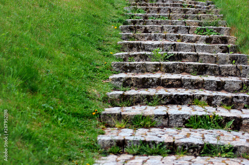 Old stone stairs on green grassy slope