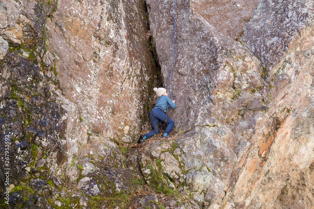 Little girl engaged in the sports climbing the natural rock