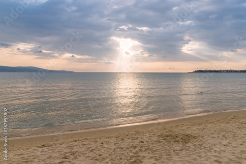 Sunbeams or sun rays peeking through the clouds at a sunrise on beautiful beach