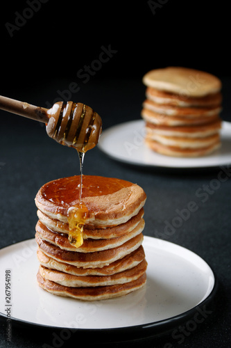 Stack of Pancakes with pouring honey on dark background. decoration concept and breakfast.