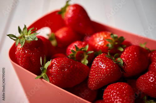 Close up of fresh juicy red strawberries in container on white table