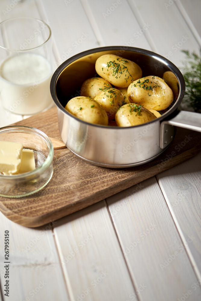 Young potatoes boiled in pot with dill and butter on wooden board Young potatoes boiled in pot with dill and butter on wooden board