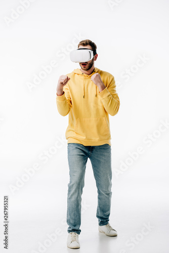 young man in blue jeans and yellow hoodie imitating boxing while using virtual reality headset on white background © LIGHTFIELD STUDIOS