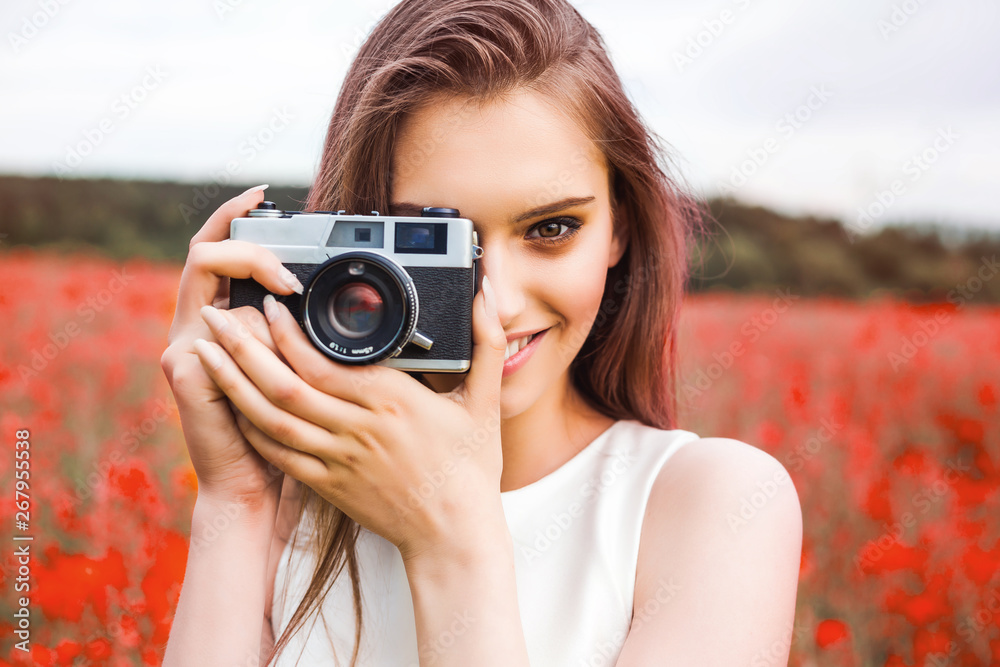 cheerful young girl in a summer dress is holding an analog film camera in front of a colorful, blooming field, concept of creativity and self-expression cheerful young girl in a summer dress is holding an analog film camera in front of a colorful, blooming field, concept of creativity and self-expression