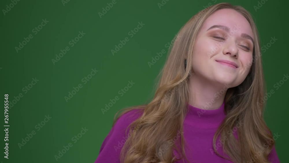 Portrait of beautiful ginger female student smiling prettily dancing to the music on green chroma background. Portrait of beautiful ginger female student smiling prettily dancing to the music on green chroma background.