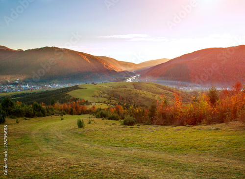 Road hiking trail in autumn colorful mountains on background of valley and magnificent sunset sky