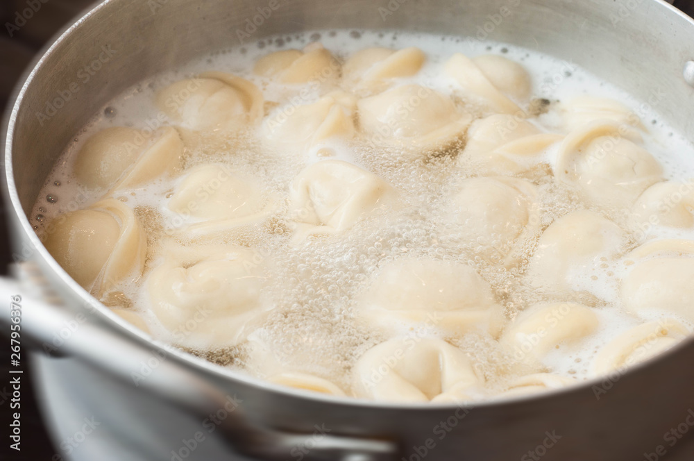Boiling water with dumplings in a saucepan on the stove in the kitchen is almost ready to eat on the table
