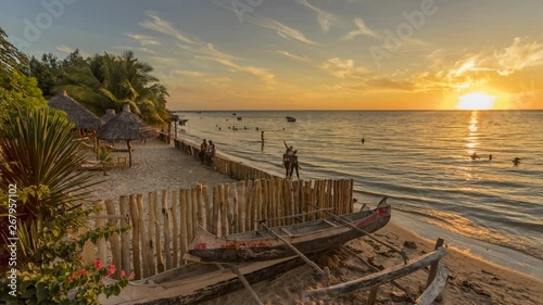 Sunset timelapse on the beach of Ifaty, Mangily, near Toliara / Tulear South West Madagascar. Tropical sandy beach, thatched huts, exotic vegetation, traditional wooden fishing boat and beautiful sky photo