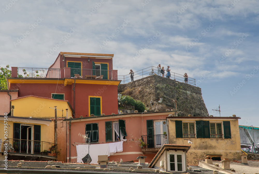 Fototapeta premium View of the colored fishermen's houses of the ancient village of Vernazza in the Cinque Terre area with tourists on the top of the medieval Castle of Doria (11th c.), Liguria, Italy