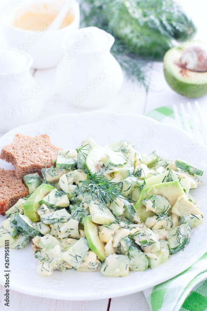 Salad with cucumbers, egg and avocado on a white plate, selective focus Salad with cucumbers, egg and avocado on a white plate, selective focus