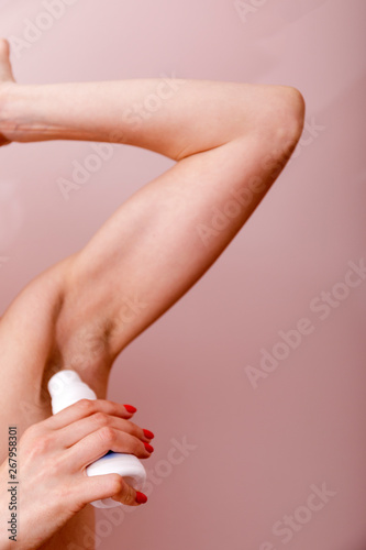 Close up of female hand preventing skin from perspiring. Girl is standing and holding antiperspirant in hand while rolling it on body.