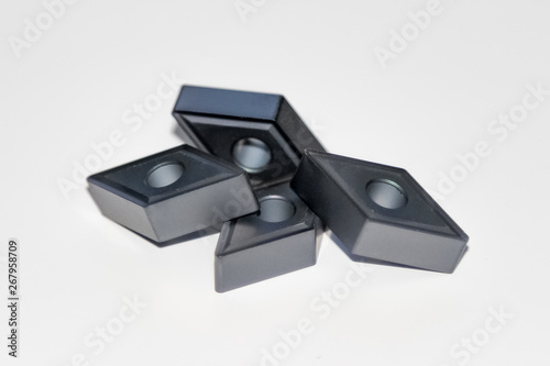 Four carbide inserts for CNC milling machine with selective focus isolated on white