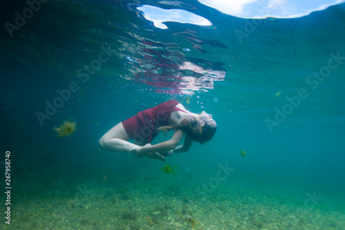 a woman in red dress dancing underwater