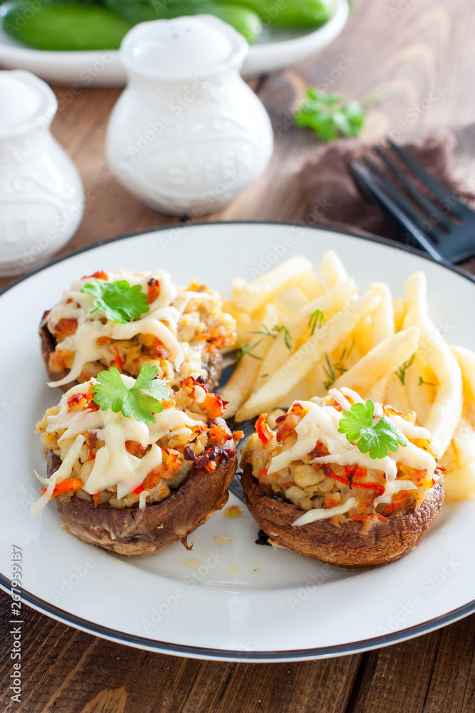 Stuffed champignons with cheese and french fries on a white plate, selective focus Stuffed champignons with cheese and french fries on a white plate, selective focus