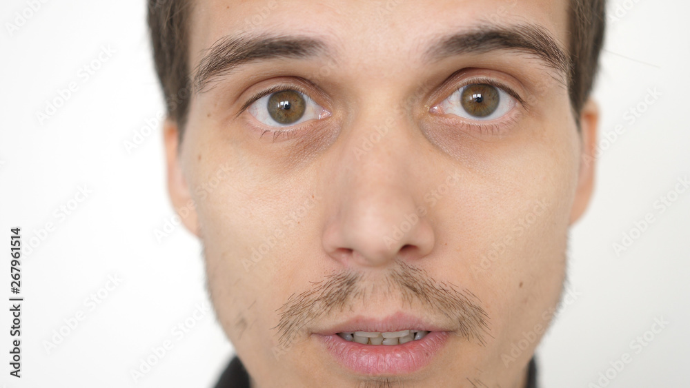 Close-up of a surprised emotional man with brown eyes looking into the camera.