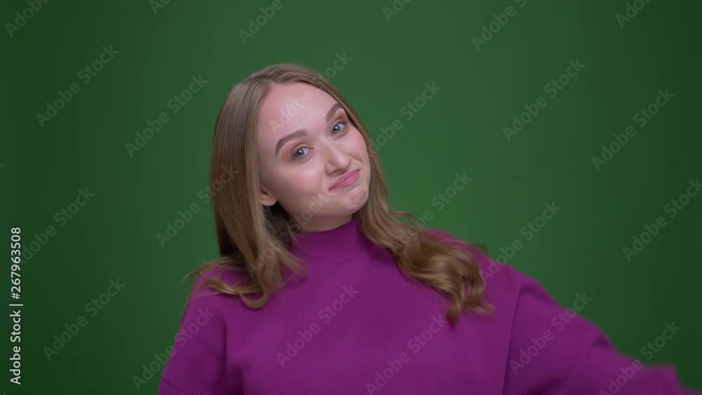 Pretty ginger female student makes ok gesture to show success and happiness on green chroma background. Pretty ginger female student makes ok gesture to show success and happiness on green chroma background.