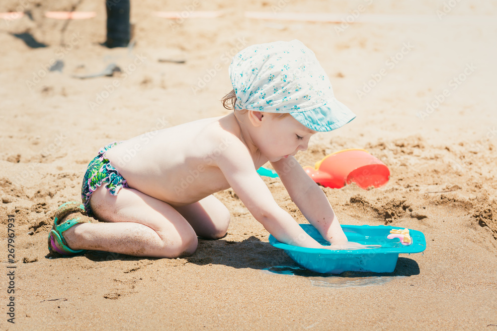 Nice baby in summer cap plays with toys on sandy beach. Nice baby in summer cap plays with toys on sandy beach.