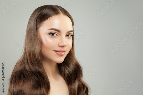 Attractive woman face. Beautiful face with clear skin and healthy brown hair. Skin care and hair care concept