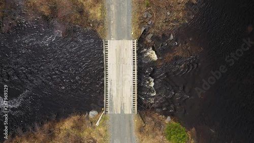 Stationary Aerial TOPDOWN of a small wooden bridge over stream in the backwoods of Maine photo