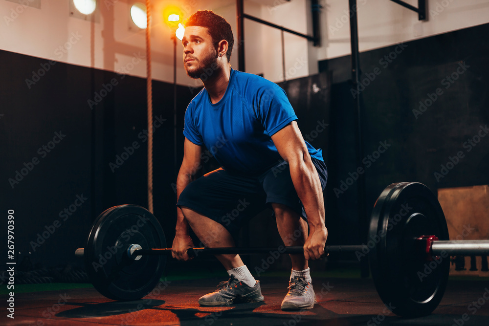 Muscular man in gym doing heavy weight exercises. Young man doing weight lifting at health club Muscular man in gym doing heavy weight exercises. Young man doing weight lifting at health club