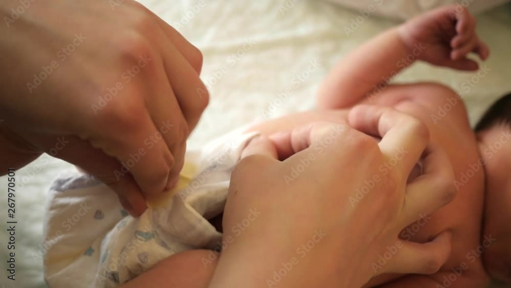 Mother hands change diaper on the changing table newborn baby couple days after birth
