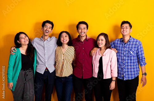 studio portrait of group of asian young friends looking at camera over yellow background photo
