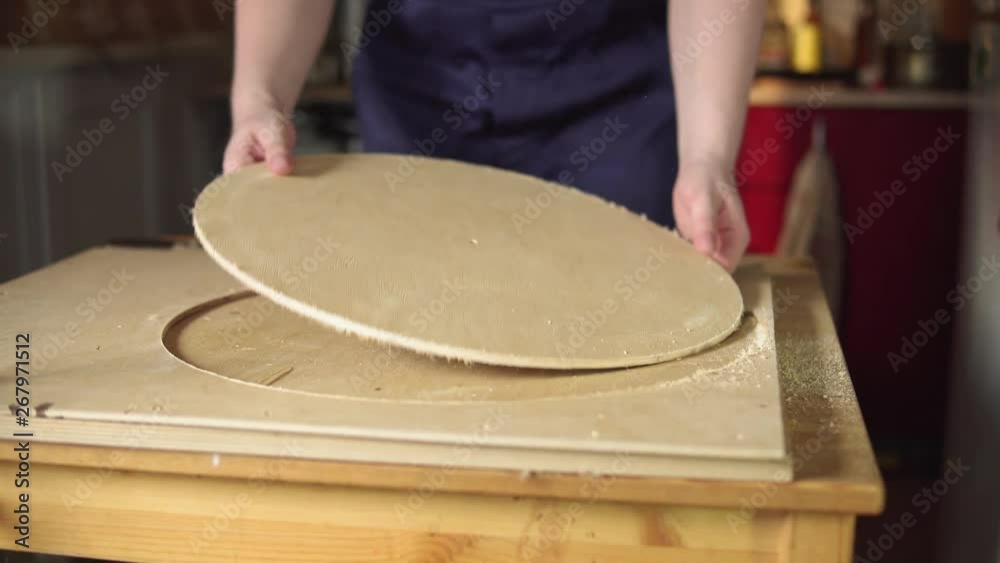 Muscular caucasian carpenter checks edges of plywood circle, which was cut by modern handheld plunge router. Young man engaged in woodworking in workshop. Muscular caucasian carpenter checks edges of plywood circle, which was cut by modern handheld plunge router. Young man engaged in woodworking in workshop.