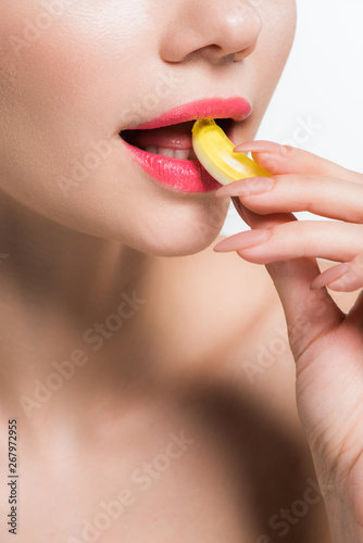 cropped view of girl eating yellow jelly candy isolated on white