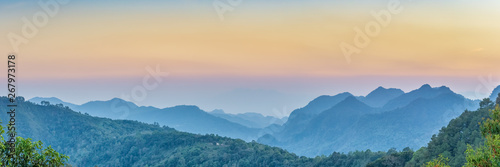 Nature Web Banner. Mountain view sunset panorama view of many hill and green forest cover with soft mist with colorful sky background, sunset at Doi Ang Khang, Chiang Mai, Thailand.