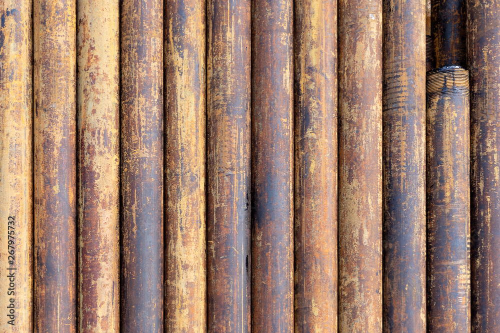 Rusty grunge pipes horizontal background. Orange corrosion rust on steel metal factory industrial pattern. Rough texture brown parallel stack close up Rusty grunge pipes horizontal background. Orange corrosion rust on steel metal factory industrial pattern. Rough texture brown parallel stack close up