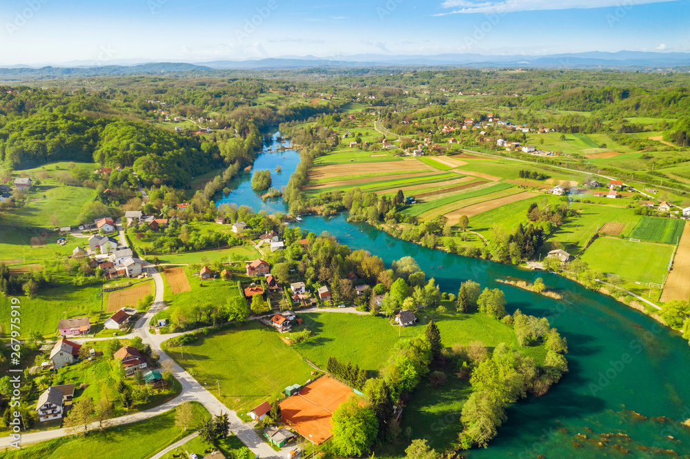 Beautiful green Mreznica river in Croatia from air, panoramic view of village and waterfalls in spring, countryside landscape
