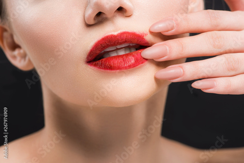 cropped view of girl touching red lips isolated on black