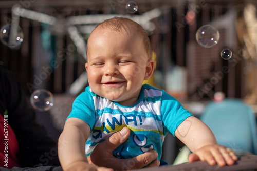 little baby portrait with soap bubbles in summer time during sunset