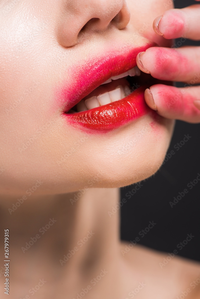 Naklejka premium cropped view of young woman removing red lipstick isolated on black