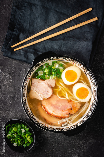 Japanese Ramen Soup with Udon Noodles, Pork, Eggs and Scallion on dark Stone Background