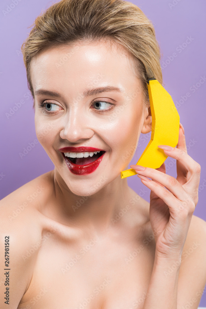 happy naked young woman holding yellow decorative banana near ear isolated on purple happy naked young woman holding yellow decorative banana near ear isolated on purple