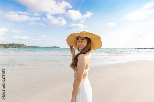 Attractive Asian young woman wearing white dress smile enjoy with summer vacation on the beach feeling so happiness and cheerful Travel in tropical beach in Thailand vacations and relaxation Concept