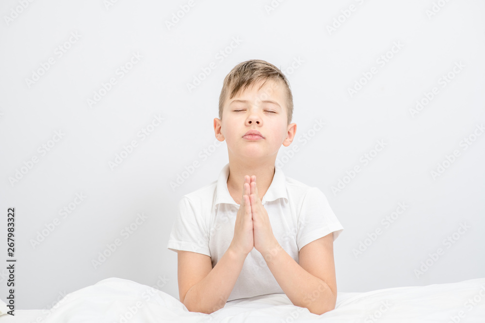 Young boy praying in bedroom before going to bed. Empty space for text Young boy praying in bedroom before going to bed. Empty space for text