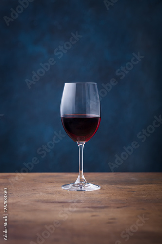 Glass of red wine on wooden table. Blue background. Copy space.