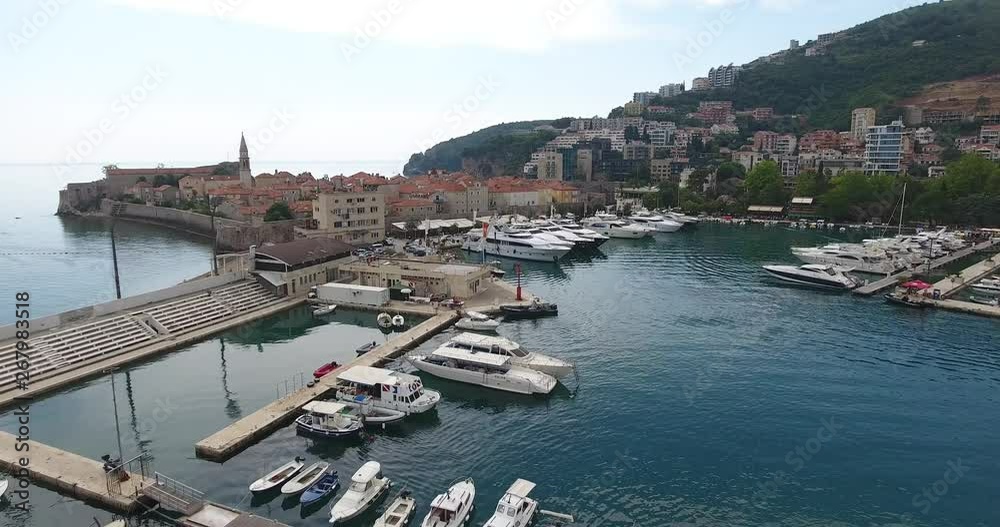 Aerial view of Budva marina with its boats, yachts and ships. Flight above the marina and waterfront, a lot of motorboats and yachts moored at the pier Aerial view of Budva marina with its boats, yachts and ships. Flight above the marina and waterfront, a lot of motorboats and yachts moored at the pier