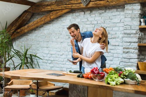 Lovely cheerful couple cook...