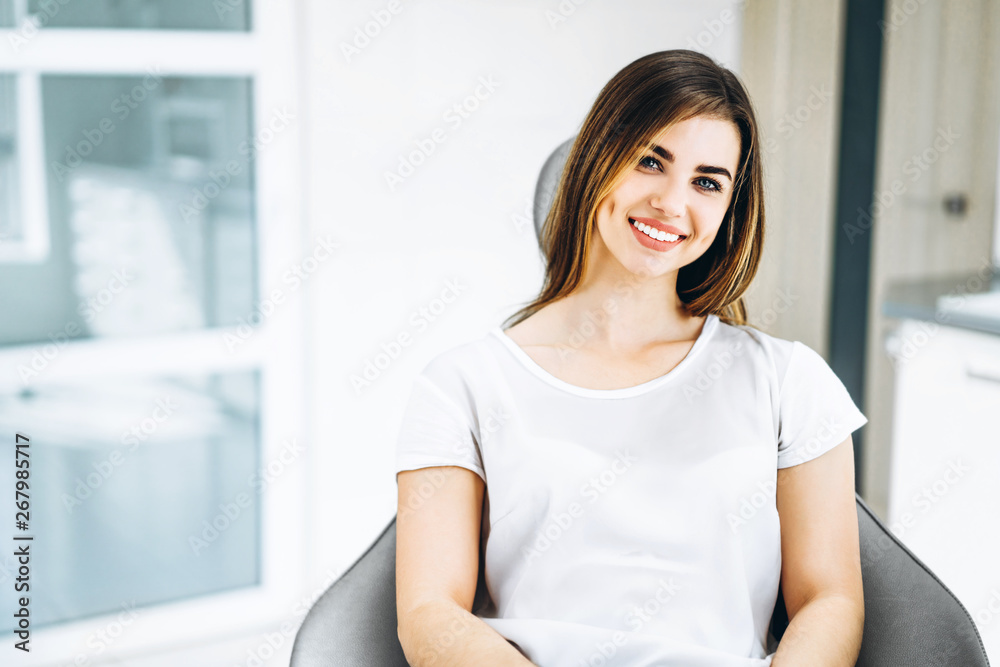 Pretty happy and smiling dental patient sitting in the dental chair at the dental office. Pretty happy and smiling dental patient sitting in the dental chair at the dental office.