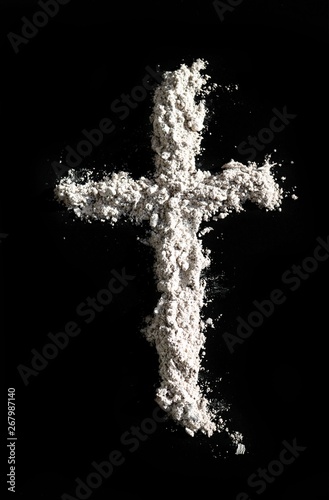 Pile of palm cross ashes in the shape of a cross isolated on black. Ash Wednesday, death, forgiveness and life in Christ concept