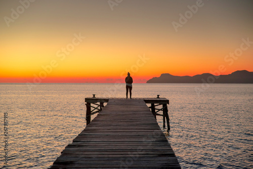 Murais de parede Alone women relax on wooden dock at peaceful lake, silhouette