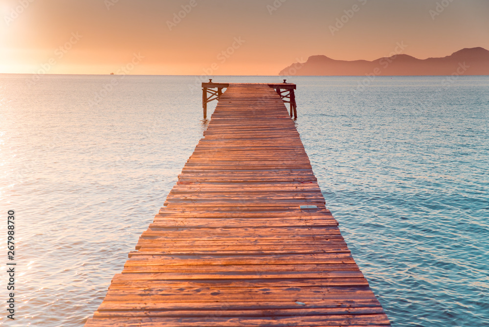 Fototapeta Warm morning light in summer vacation holiday resort. Pier in orange sunrise colors