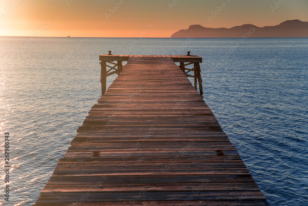 Pier in beautiful summer sunrise light. Warm orange colors, Mallorca, Spain