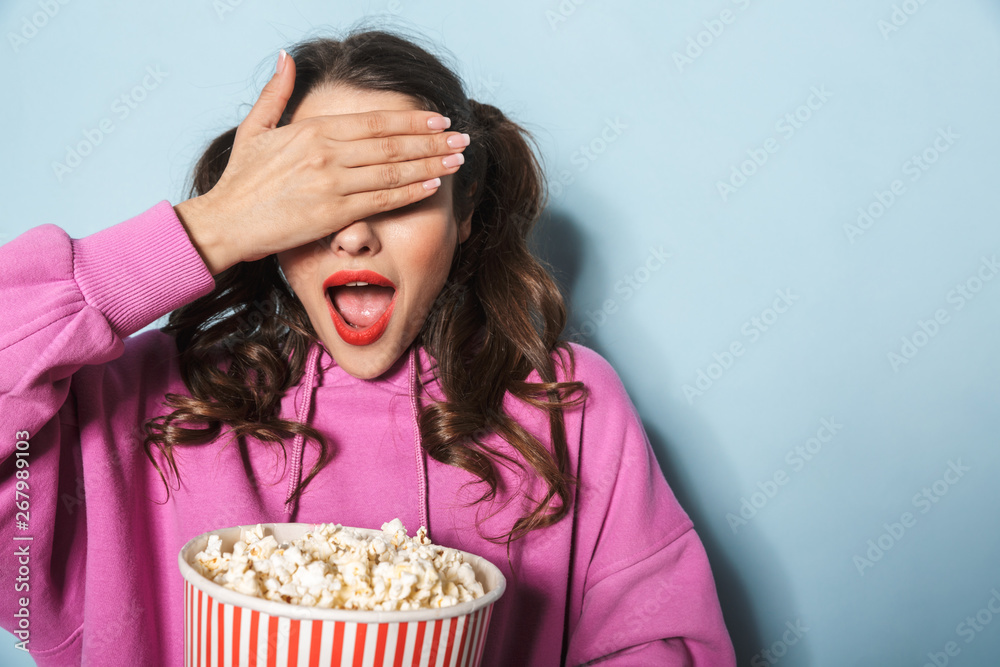 Portrait of teenage young woman with two ponytails smiling while holding popcorn bucket Portrait of teenage young woman with two ponytails smiling while holding popcorn bucket