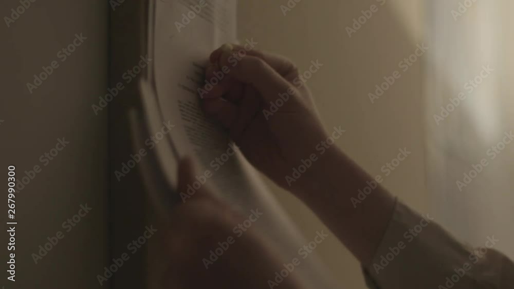 Handheld, close up shot of hands tacking up paper on a bulletin board.