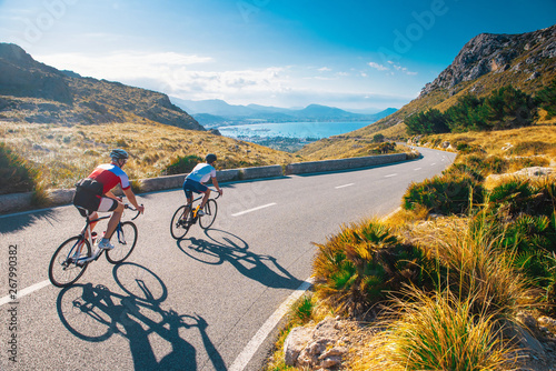 Road cycling photo. Two triathlete train in beautiful nature. Sea and mountains in background. Alcudia, Mallorca, Spain photo